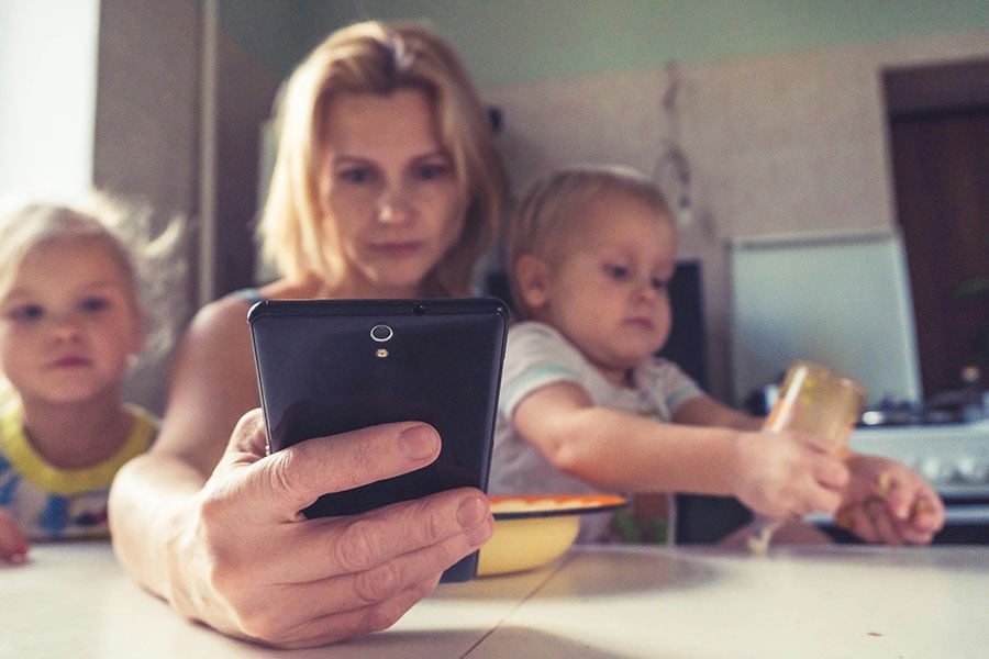A mother searches for resources while caring for her two children. (Unsplash/Vitolda Klein)